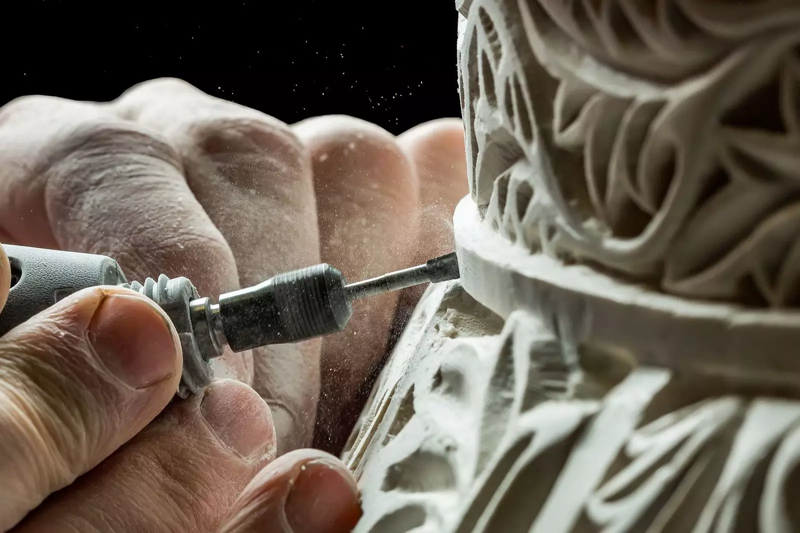 Crop hands carving ornament on plaster